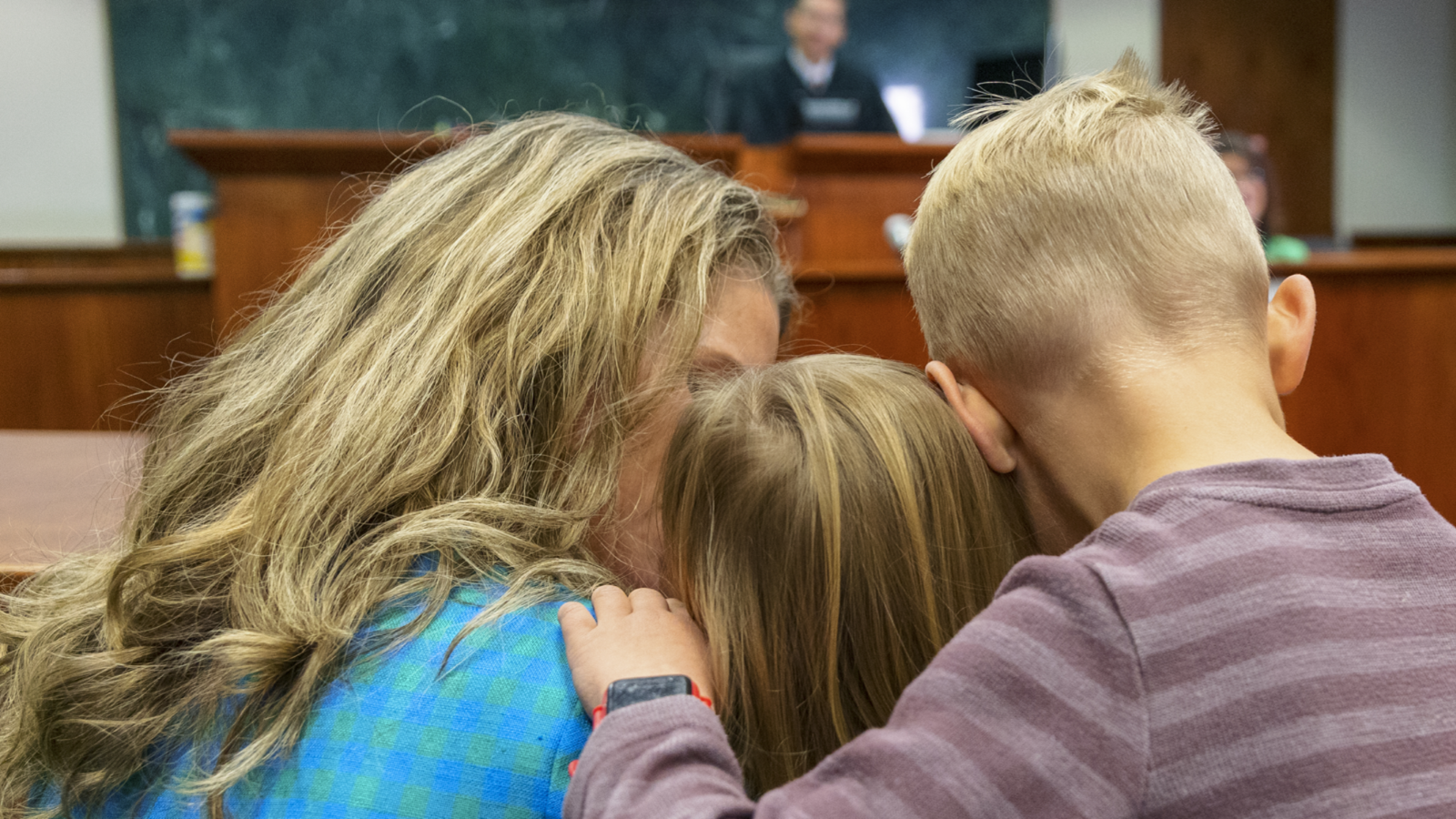 An adult and two children in a courtroom