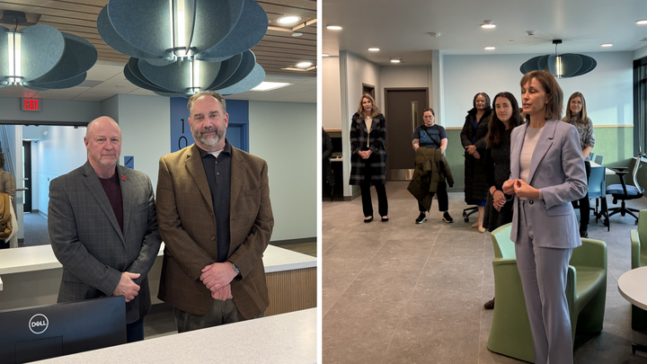 Two men standing side-by-side, and a woman in a light gray suit speaking to a room of people.