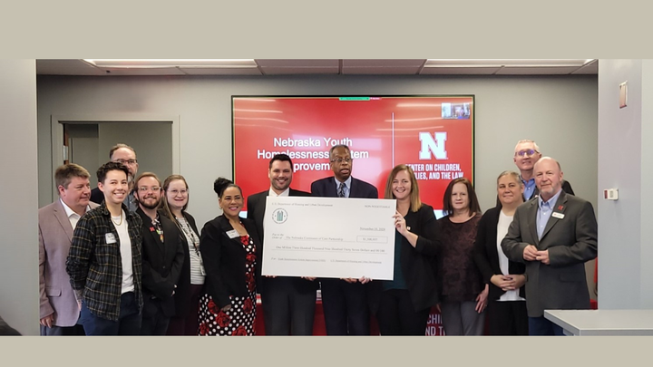 A group of people holding a large check at the YHSI launch event.